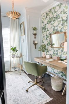 a room with a desk, chair and mirror on it in front of a floral wallpaper