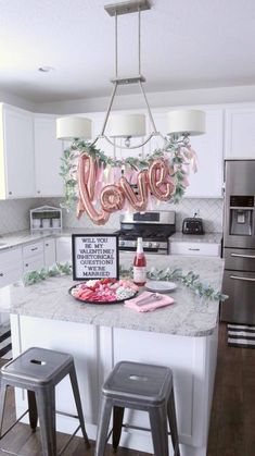 a kitchen island with two stools in front of it and a love sign on the top