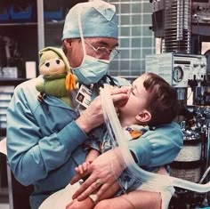 a man in scrubs is holding a small child with an oxygen tube attached to his mouth