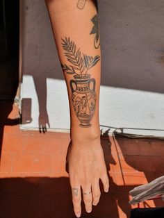 a person's arm with tattoos on it and a vase in the middle of their arm