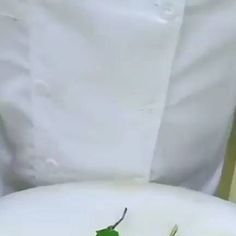 a close up of a person wearing a white shirt and holding a plate with food on it