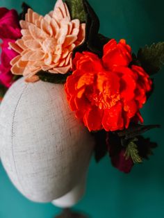 a white mannequin head with flowers on it's top and green background