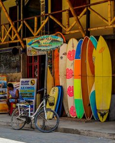 a bike parked next to a building with surfboards on it