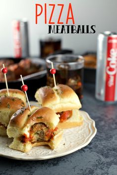 two mini pizza meatballs on a plate with toothpicks in the middle and coke cans behind them