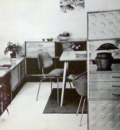 an old black and white photo of a room with desks, chairs, and cabinets