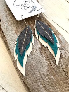 "Handcrafted leather dangly earrings. Each feather is individually cut and sewn by me. They hang on stainless steel hooks and are approximately 4\" long including the hook. Hooks are hypoallergenic stainless steel.  The delicate layers are gray, teal blue, and cream. Fantastically lightweight and fun!  Due to the nature of handmade products, no two earrings will be exactly the same. Your earrings will be *almost* exactly like this set but not exactly. I have done my best to edit the photos to as Wire Wrapped Turquoise, Leather Feather Earrings, Handmade Leather Jewelry, Leather Jewelry Diy, Leather Ideas, Leather Projects, Dangly Earrings, Recycled Crafts, Feather Earrings