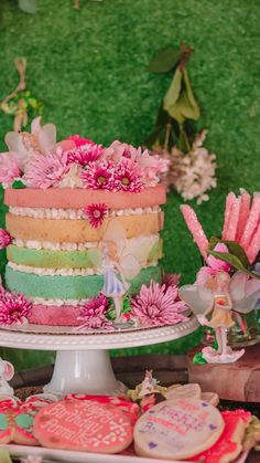 there is a cake on the table with pink flowers and other decorations in front of it