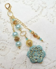 a close up of a key chain on a lace table cloth with beads and charms