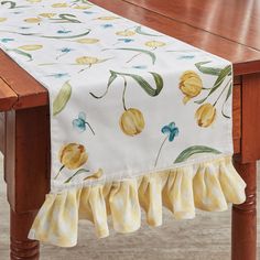 a wooden table topped with a yellow and blue flowered table runner on top of it