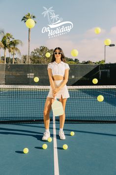 a woman standing on top of a tennis court holding a racquet and ball