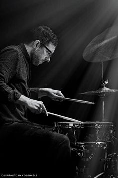 a man playing drums in front of a spotlight