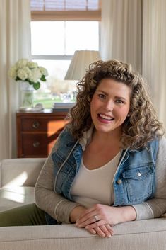 a woman with curly hair sitting on a couch