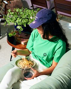 a woman sitting on a couch holding a bowl of food