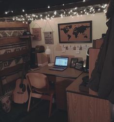 a desk with a laptop computer on top of it next to a wall mounted world map