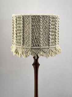 a crocheted lamp shade on a wooden base