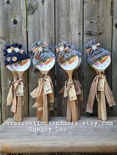 three wooden spoons with flowers on them are sitting on a bench in front of a fence