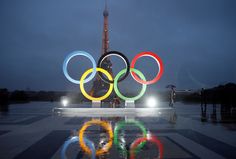 the olympic rings are lit up in front of the eiffel tower