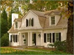 a white house with black shutters on the front and windows in the side yard