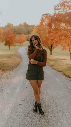 a woman standing in the middle of a road with her arms crossed and looking at the camera