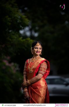 a woman in a red and gold sari posing for the camera with her hands on her hips