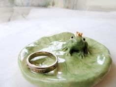 a frog sitting on top of a leaf with a wedding ring in it's mouth