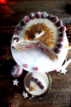 a cake with white frosting and berries on it sitting on top of a wooden table