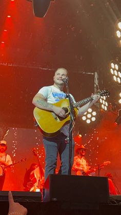 a man with a guitar on stage at a concert