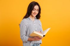 a young woman is reading a book while standing against a yellow background with her eyes closed