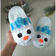 someone is holding up their crocheted snowman slippers