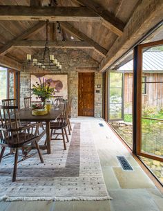 a dining room table and chairs in front of a brick wall with glass doors leading to the outside