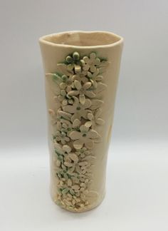 a white vase with green flowers on it