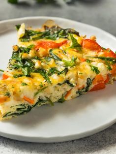 a slice of quiche on a white plate with green garnish and tomatoes