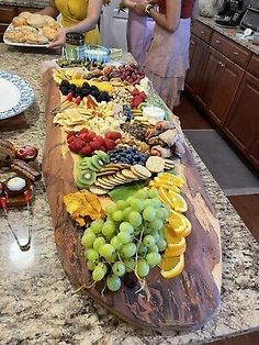 two women are standing in front of a table full of fruits and cheeses on it