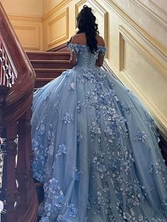 a woman in a blue dress walking down some stairs