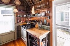 a kitchen with wood paneling and open shelves on the wall, along with a stove top oven