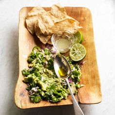 a wooden plate topped with guacamole and tortilla chips