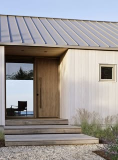 a wooden door sitting on the side of a white building next to a gravel field