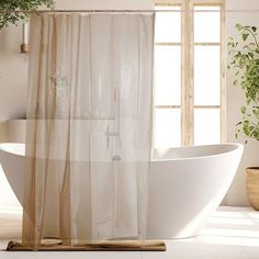 a white bath tub sitting next to a window in a bathroom with plants on the floor