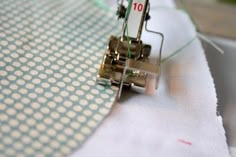 the sewing machine is on top of the white fabric with blue and white dots in it