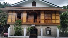 an old building with wooden balconies on the front and second story, surrounded by greenery