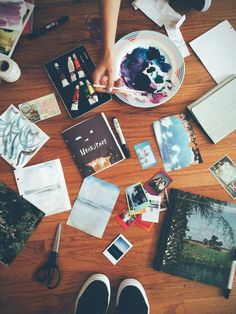 a person is painting on a table with other items around it, including cards and pens