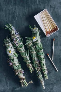 several sticks with flowers tied to them next to some matches on a black table top