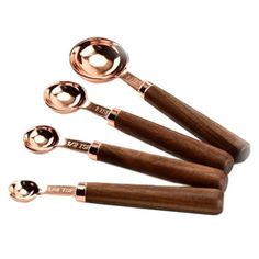 four measuring spoons with wooden handles on white background