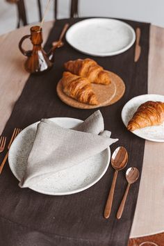 the table is set with croissants and silverware