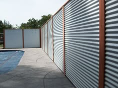 an empty swimming pool next to a fenced in area with metal slats on it