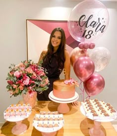 a woman standing in front of a table filled with cakes and desserts