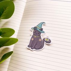 an open notebook with a sticker of a cat wearing a witches hat