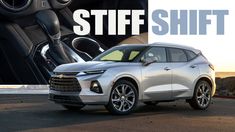 a silver chevrolet suv parked in front of a large poster with the words stiff shift on it