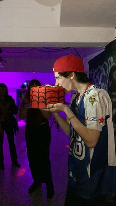 a woman holding a cake in front of her face while wearing a red beanie