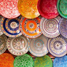 many colorful plates are stacked on top of each other in the same color and pattern